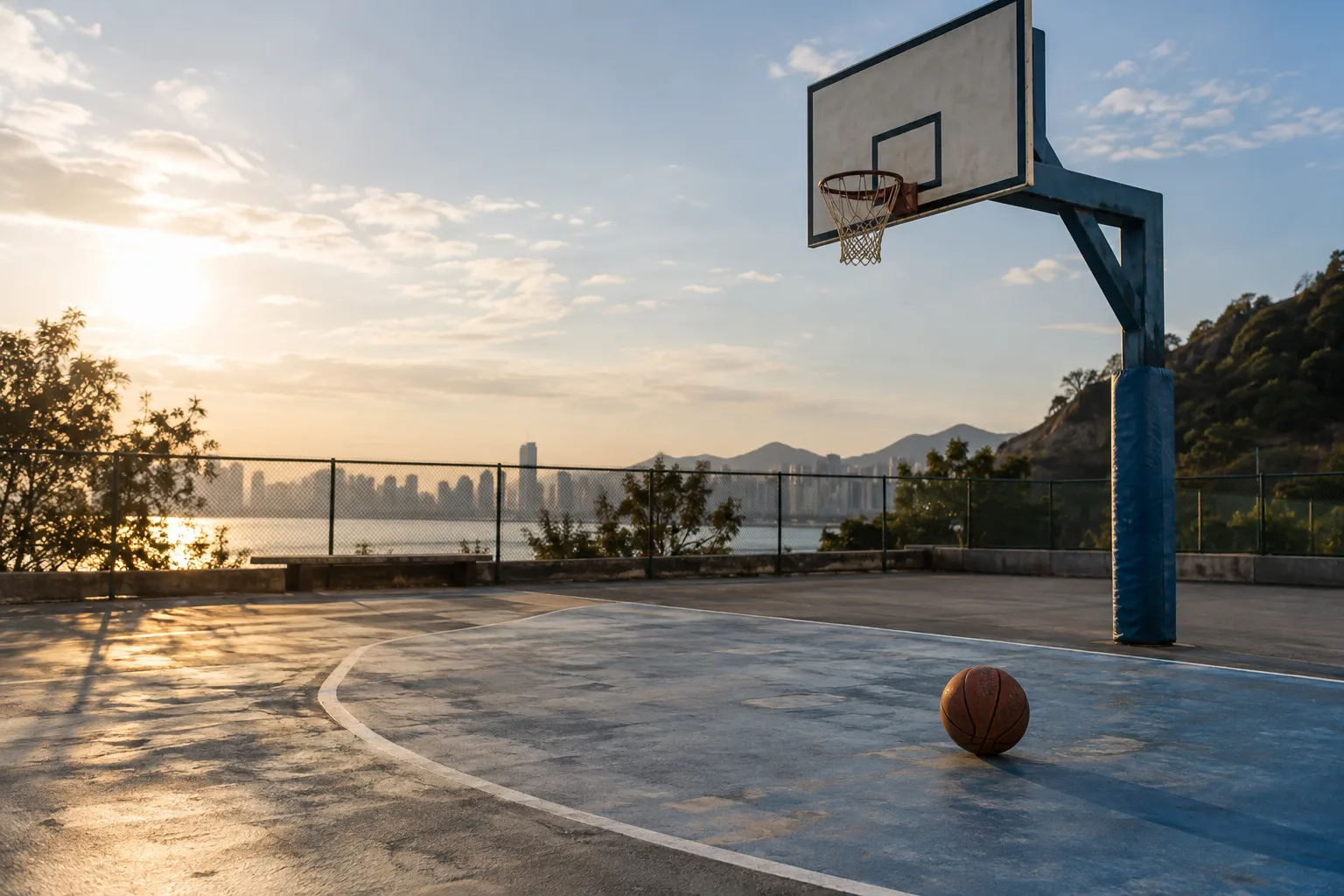 A basketball beneath the hoop, casting a long shadow